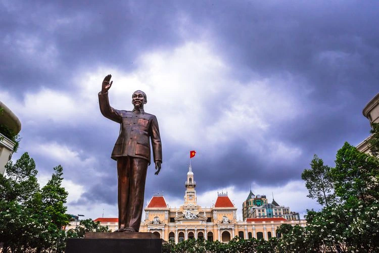 Estátua de Ho Chi Minh em Ho Chi Minh City, no Vietnã, com o prédio da prefeitura ao fundo, símbolo histórico do comunismo vietnamita e referência em debates sobre a diferença entre socialismo e comunismo.