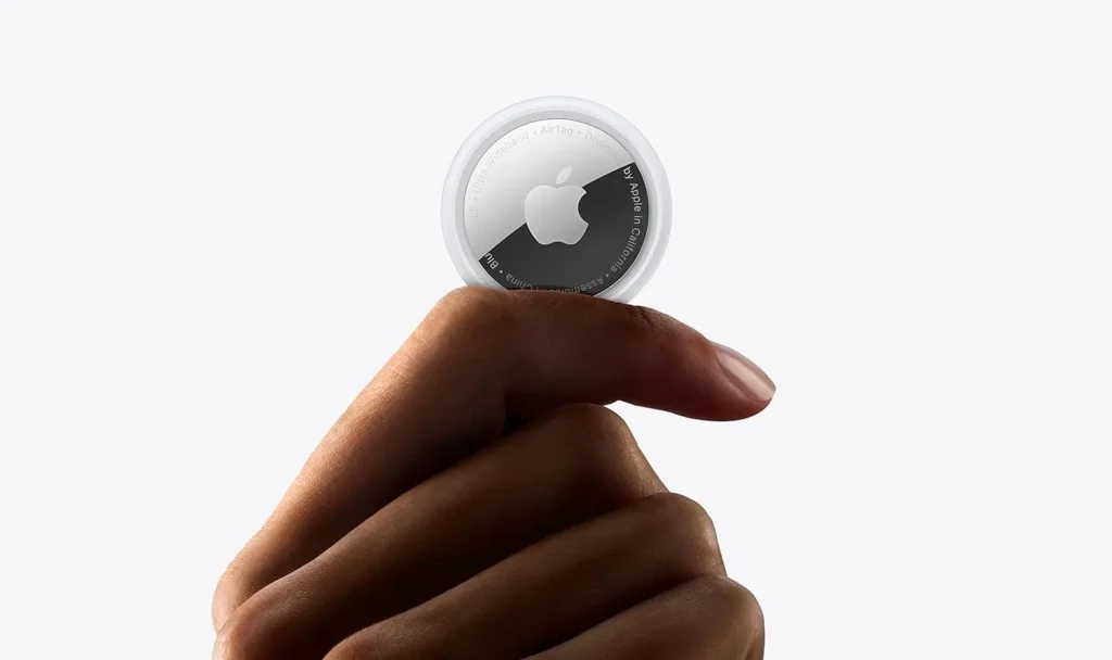 Pessoa segurando um AirTag da Apple entre os dedos, imagem ilustrativa usada para explicar a diferença entre o AirTag 2 e o AirTag original e como identificar cada geração do rastreador.