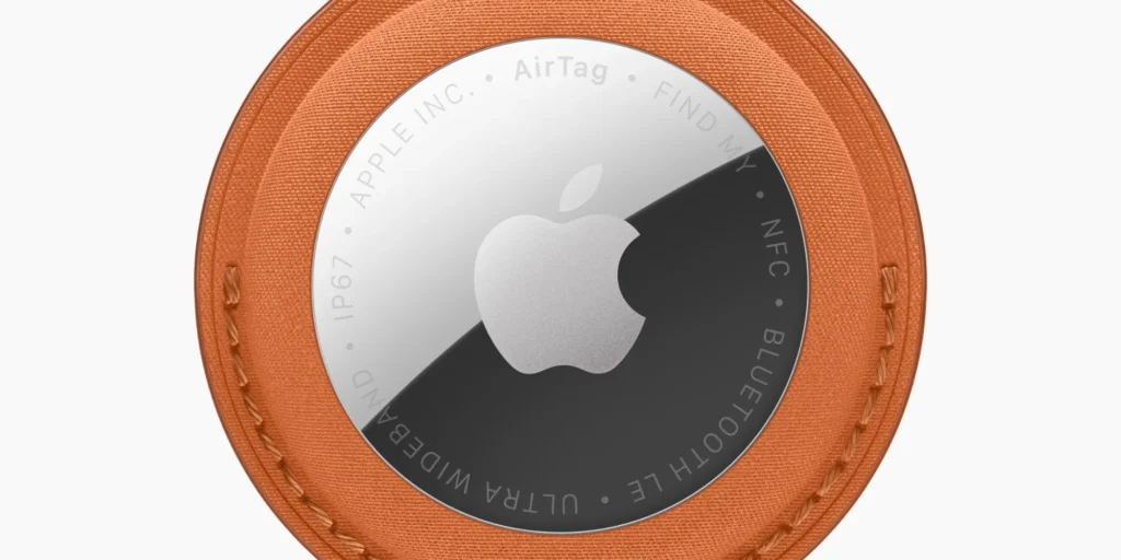 Vista traseira do AirTag 2 mostrando a diferença entre o AirTag 2 e o AirTag original, com inscrições em letras maiúsculas como FIND MY, NFC, BLUETOOTH LE, ULTRA WIDEBAND e certificação IP67 gravadas ao redor do logotipo da Apple.