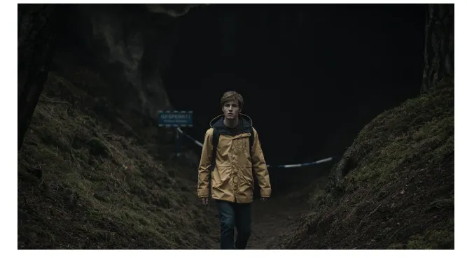 Cena da série Dark mostrando Jonas Kahnwald em frente à caverna de Winden, ambiente sombrio e misterioso que simboliza viagens no tempo, em comparação conceitual com Stranger Things no contexto Dark vs Stranger Things.