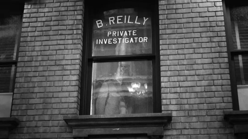 Janela com a inscrição “B. Reilly Private Investigator” em prédio de tijolos em preto e branco, destacando que O Ben Reilly de Spider-Noir é muito diferente de Peter Parker ao atuar como investigador particular em estilo noir.