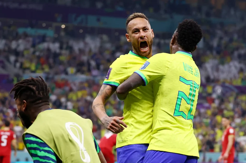 Neymar comemora gol ao lado de Vinícius Júnior com a camisa da Seleção Brasileira, imagem que ilustra a comparação Vinícius Júnior vs. Neymar e a diferença entre suas carreiras no futebol europeu.