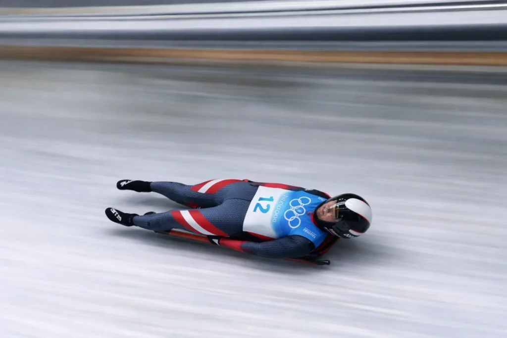Atleta de luge descendo a pista de gelo deitado de costas, exemplo para entender qual é a diferença entre bobsleigh, skeleton e luge.